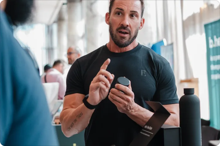 A coach talking through recovery while holding a REM+ bottle